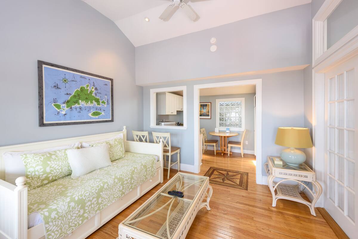 A living room with a sofa, a coffee table, a dining table with chairs, a lamp, and a framed map on the wall.
