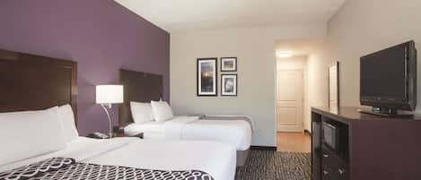 A hotel room with two beds, a television, a desk, and a dresser.