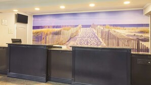 Un espace d’accueil agrémenté d’une grande fresque représentant une scène de plage, d’un comptoir de réception et d’un téléviseur à écran plat fixé au mur.