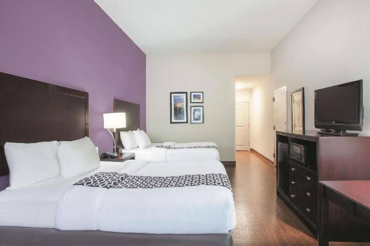 A hotel room with two beds, a TV, a desk, and a dresser.