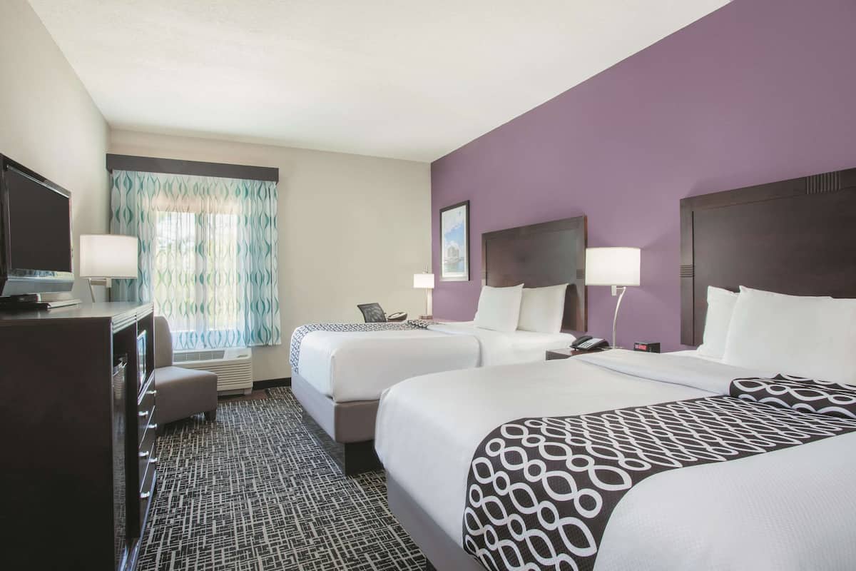 Ein Hotelzimmer mit zwei Betten, einem Schreibtisch und einem Fernseher.