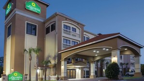 Un bâtiment de la chaîne La Quinta Inn & Suites, avec une structure à deux étages, une entrée couverte et une enseigne indiquant le nom de l’établissement.