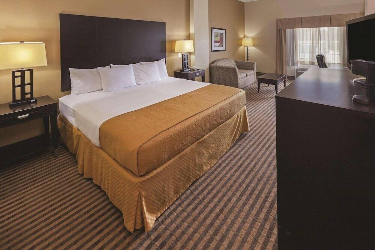A hotel room with a large bed, a desk, a chair, and a television.