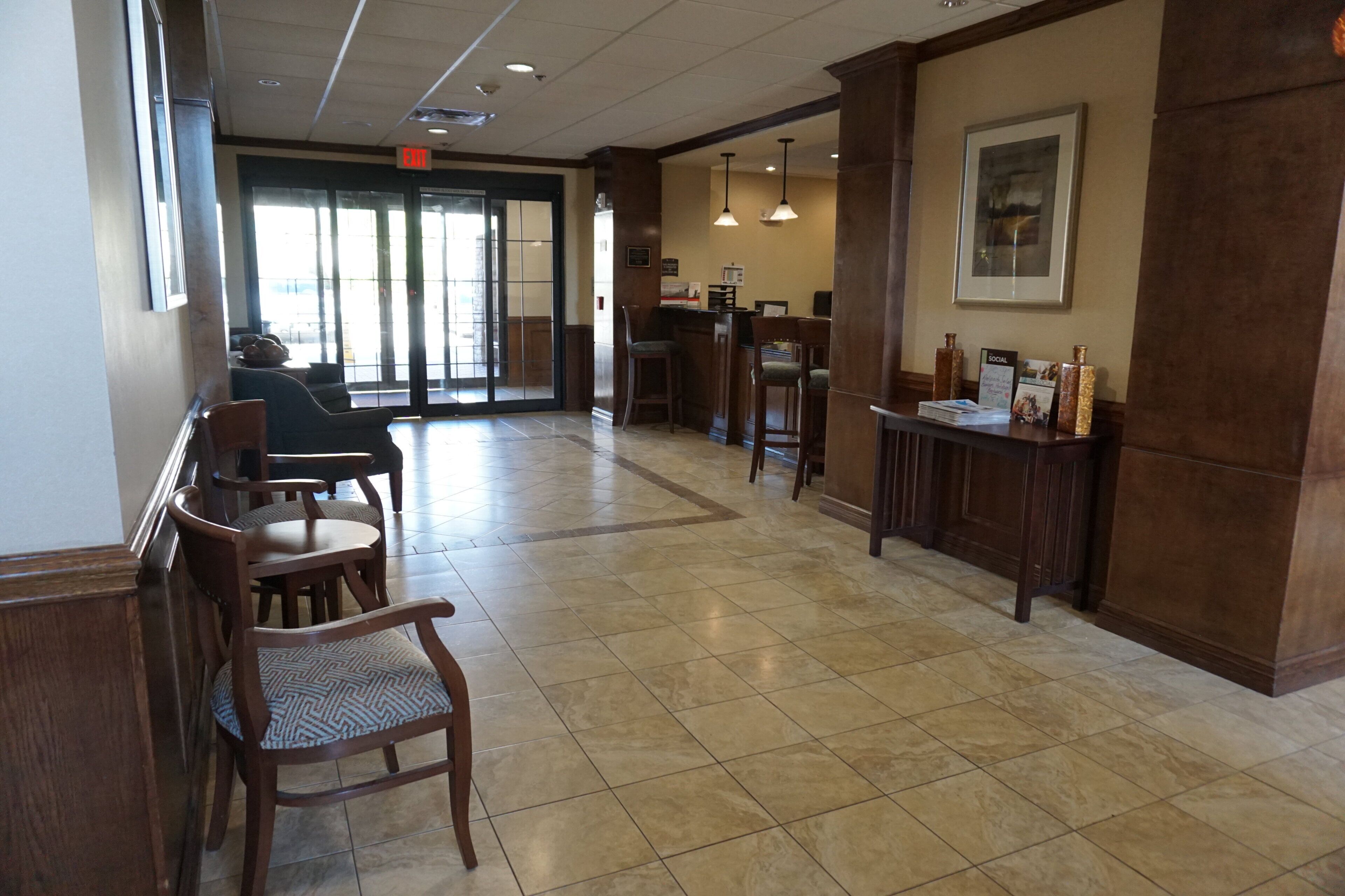 A lobby with a reception desk, seating area, and a door leading outside.