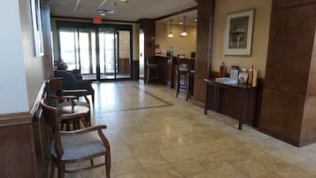 A lobby with a reception desk, seating area, and a door leading outside.