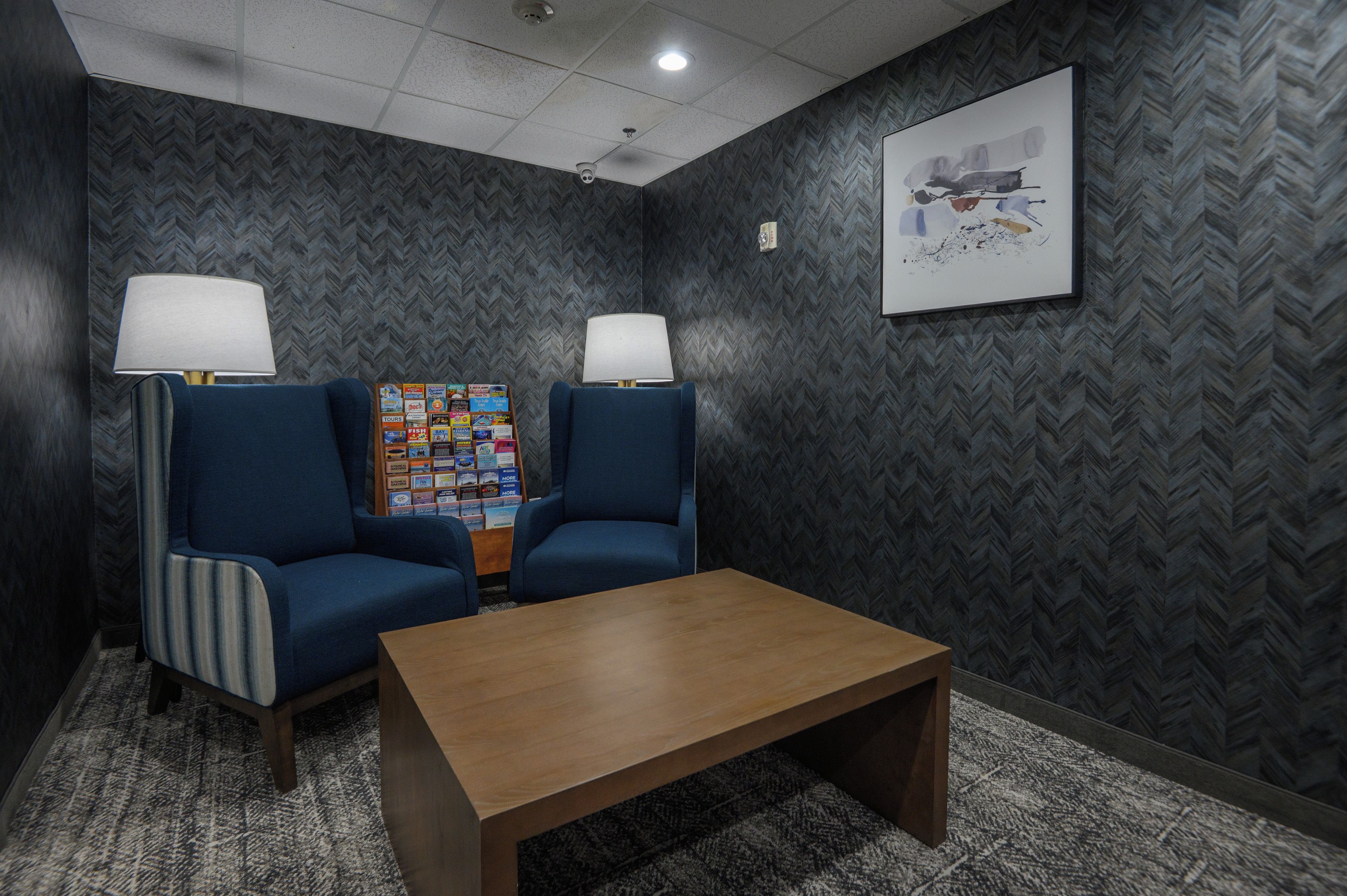Un área de espera con dos sillones, una mesita y un tablón de anuncios con varios objetos.