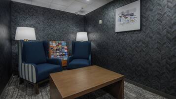 Un área de espera con dos sillones, una mesita y un tablón de anuncios con varios objetos.