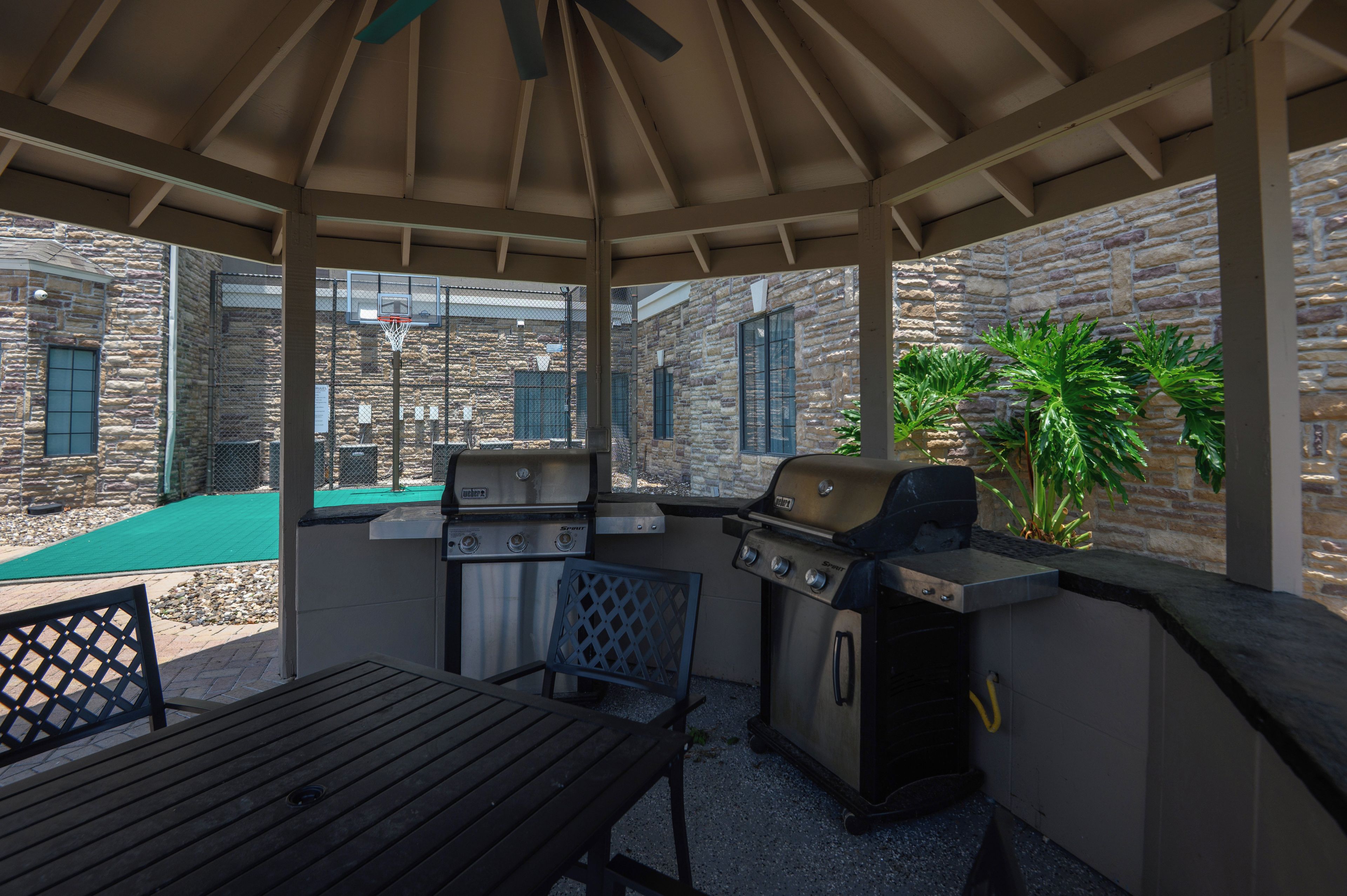 Une terrasse extérieure avec un barbecue, une table et une chaise.