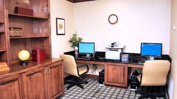 Una oficina profesional con dos escritorios, computadoras, una impresora y un reloj en la pared.