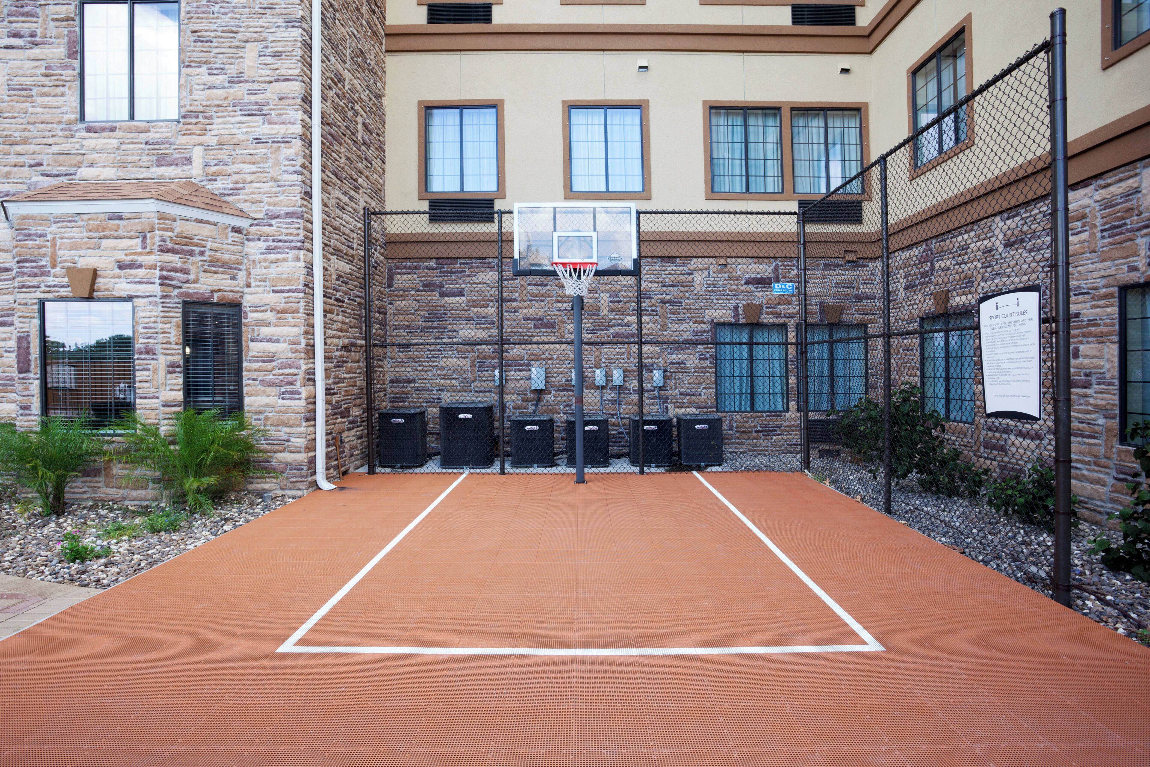 An outdoor basketball court with a stone building in the background.
