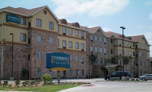 A Staybridge Suites hotel with a brick facade, multiple windows, and a signboard. - Staybridge Suites Corpus Christi by IHG (Corpus Christi)