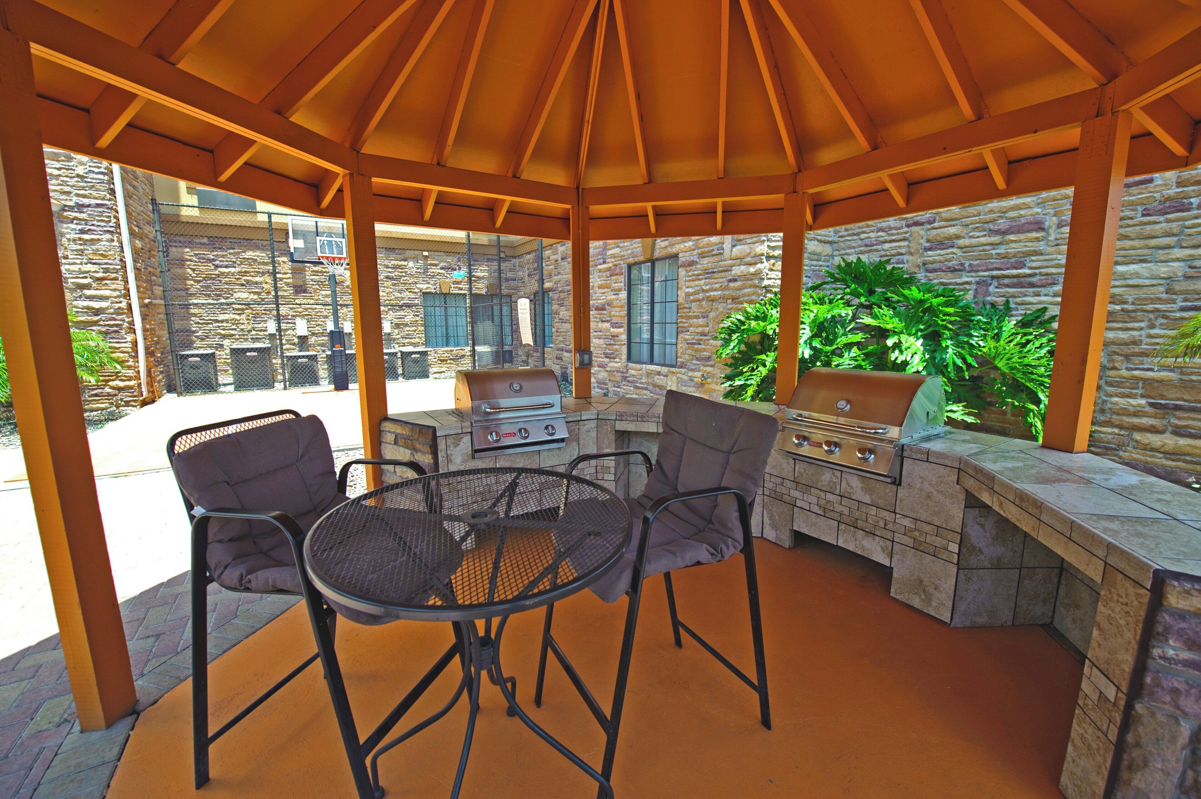 Une terrasse extérieure dotée d’un espace salon couvert, d’un barbecue et d’un panier de basketball.