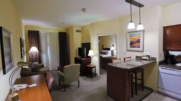 Habitación de hotel con sala de estar, kitchenette, mesa de comedor y dormitorio separado.