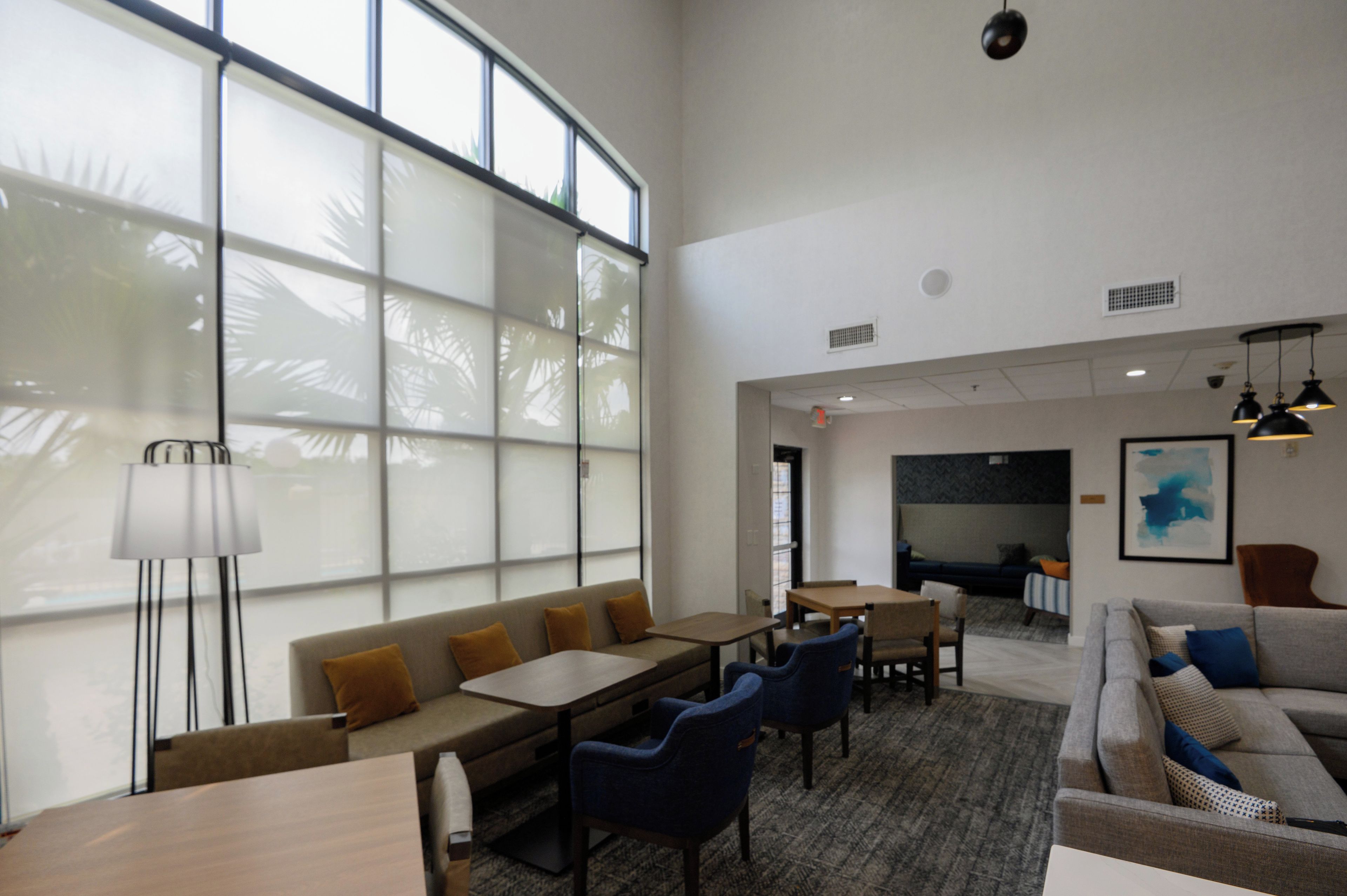 A spacious lounge area with a large window, seating arrangements, and a dining table.