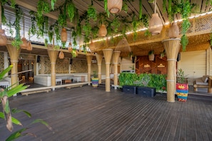 Un espace intĂ©rieur vaste et lumineux, agrĂ©mentĂ© de plantes suspendues, de meubles en osier et dâun plancher en bois.