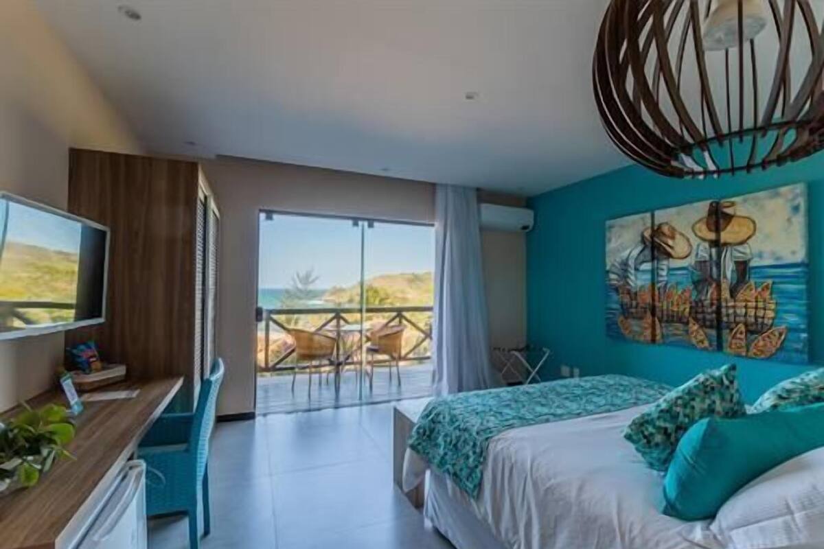 A bedroom with a bed, a desk, a TV, and a balcony with a view.