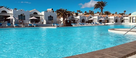 Una piscina al aire libre, sillones reclinables de piscina