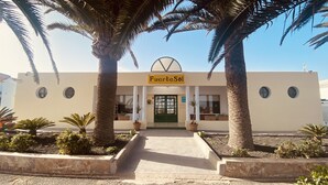 Un hôtel appelé « Fuerte Sol », doté d’une façade moderne, de palmiers et d’une entrée centrale.