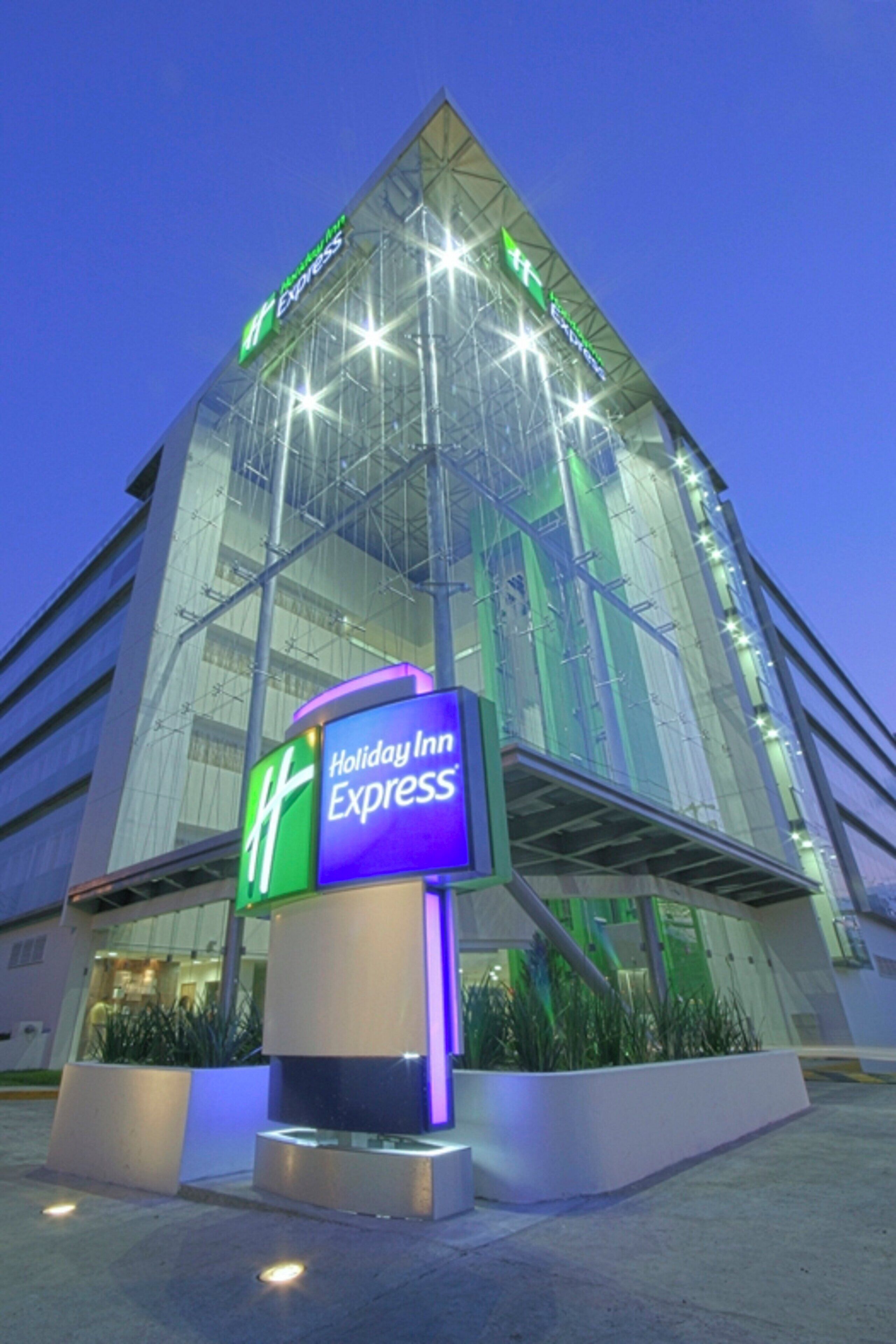 En Holiday Inn Express bygning med en moderne glasfacade og et tydeligt skilt.