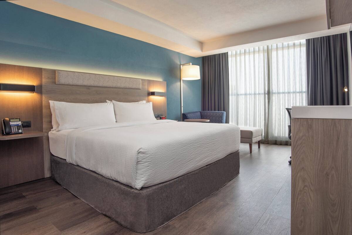 A hotel room with a large bed, bedside tables, a desk, and a chair.