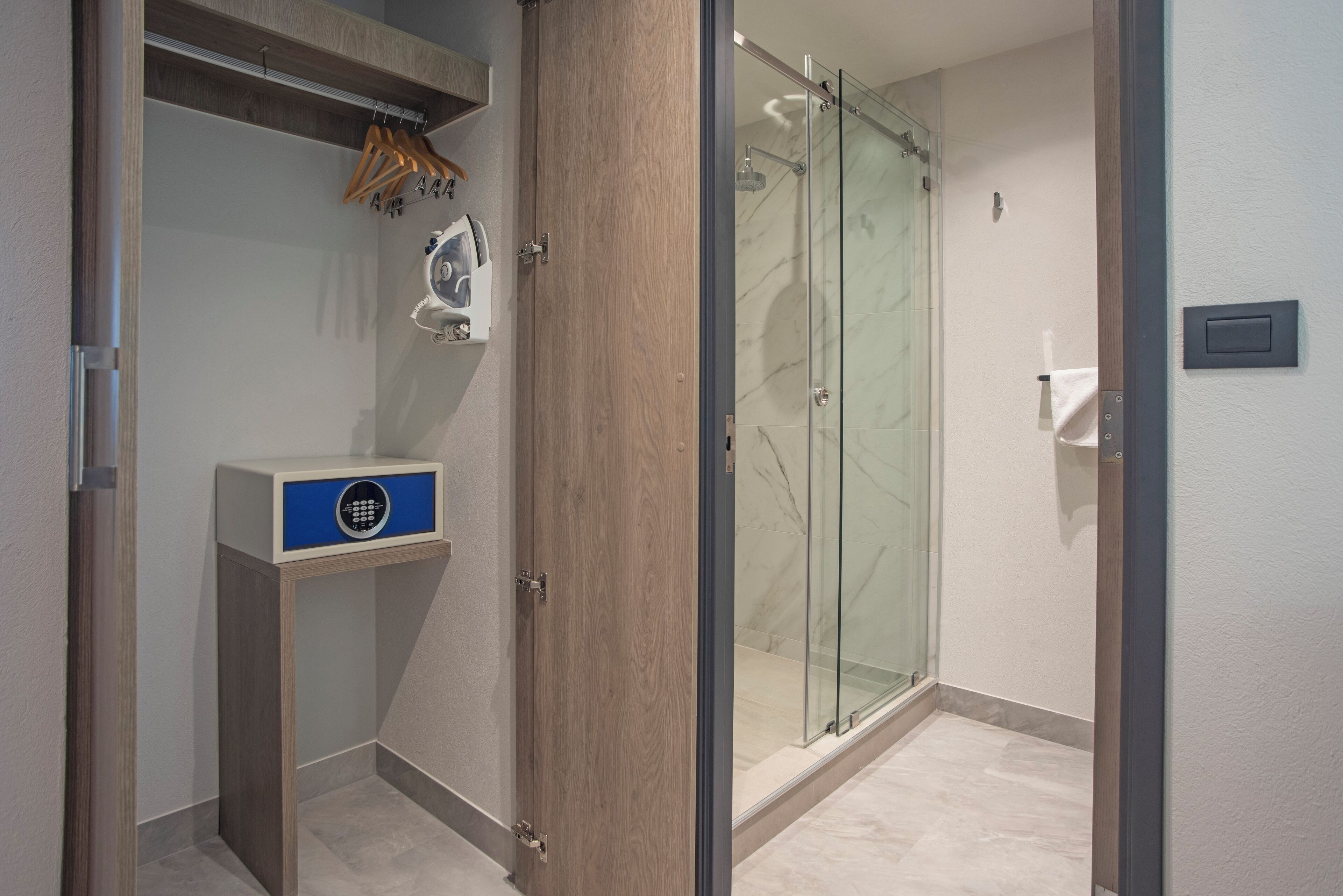 A modern bathroom with a glass shower enclosure, a wooden vanity with a blue cabinet, and a towel rack.