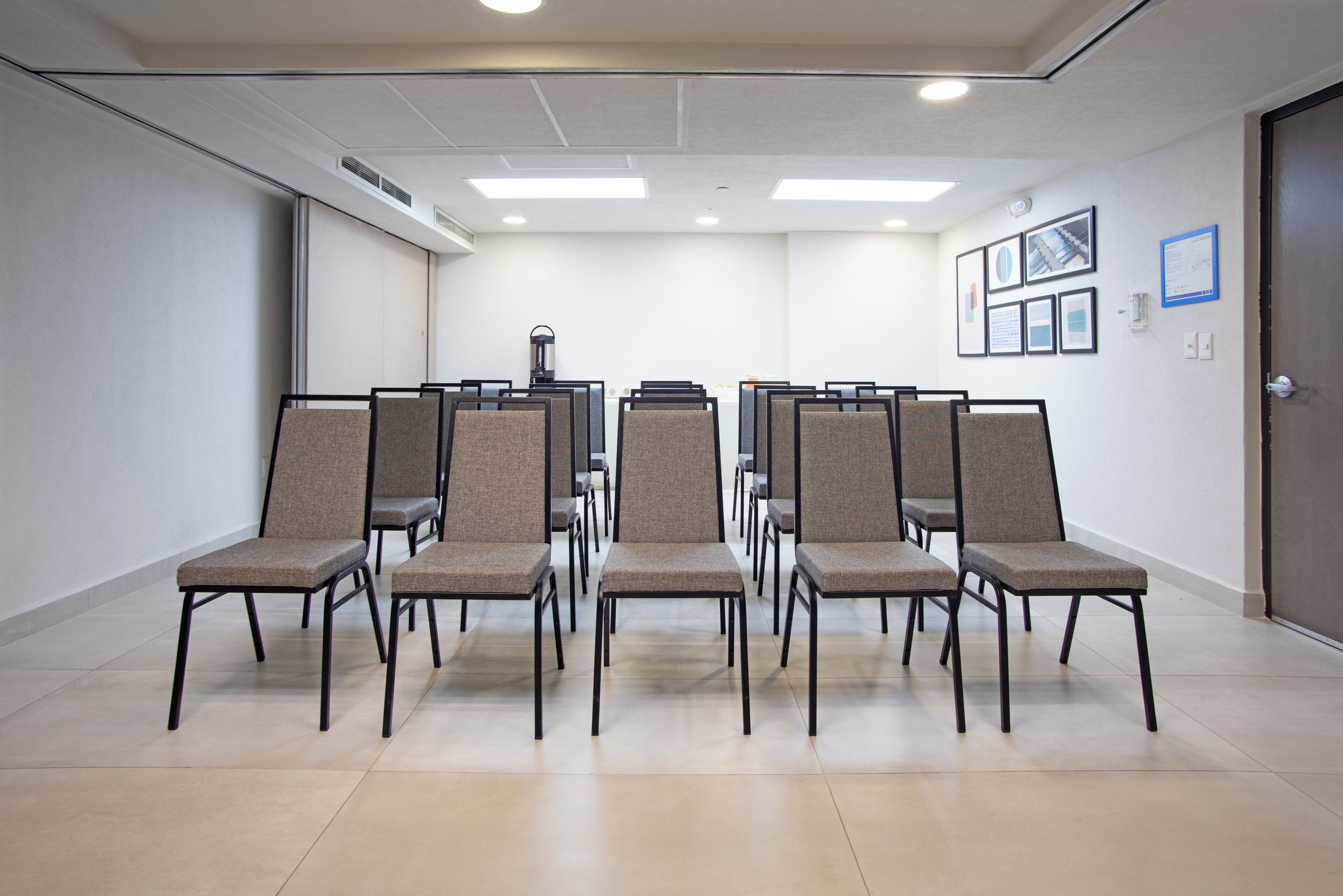 A conference room with rows of chairs, a projector, and framed pictures on the wall.