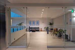 A modern lobby with a glass partition, a reception desk, seating area, and artwork on the walls. - Holiday Inn Express Guadalajara Expo by IHG (Guadalajara)