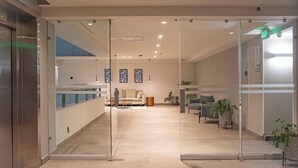 A modern lobby with a reception desk, seating area, and glass doors leading to elevators. - Holiday Inn Express Guadalajara Expo by IHG (Guadalajara)