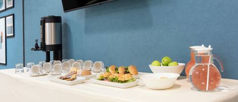 A buffet table with various food items, a coffee machine, and a pitcher of water.