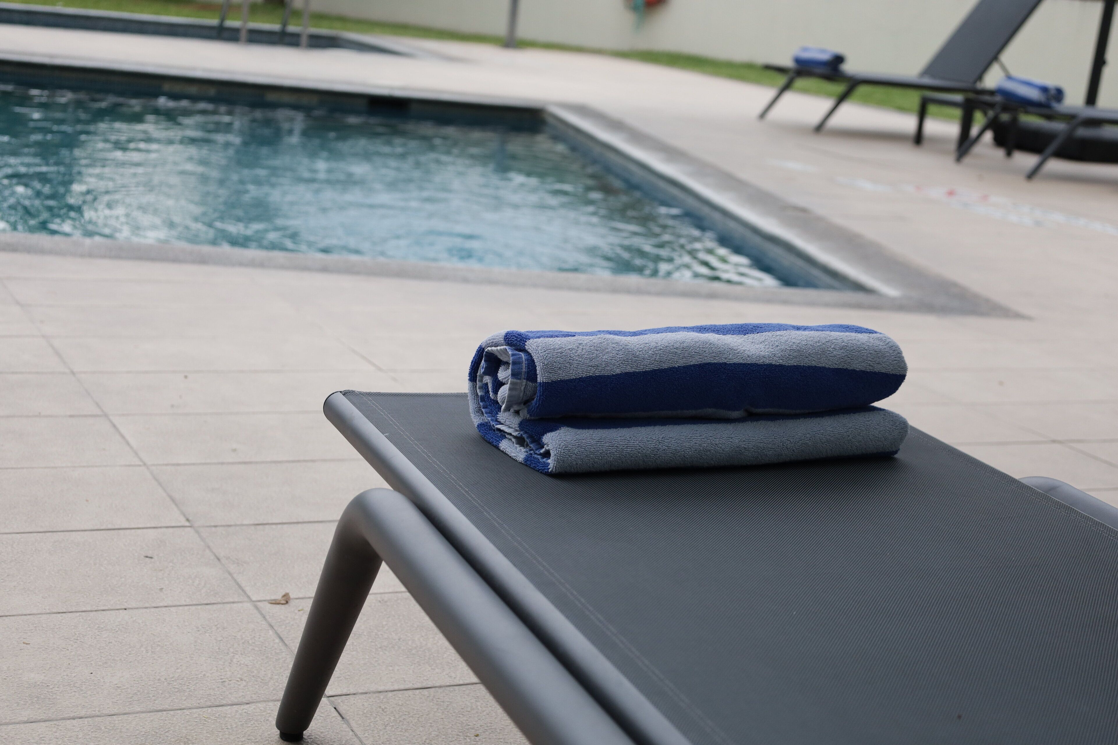 A poolside area with a lounge chair and towels.