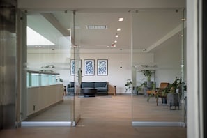 A modern interior with a glass partition, a sofa, a coffee table, and potted plants. - Holiday Inn Express Guadalajara Expo by IHG (Guadalajara)