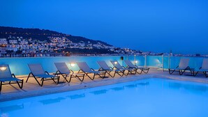 A swimming pool with lounge chairs and a city view at dusk. - NH Nice (Nice)