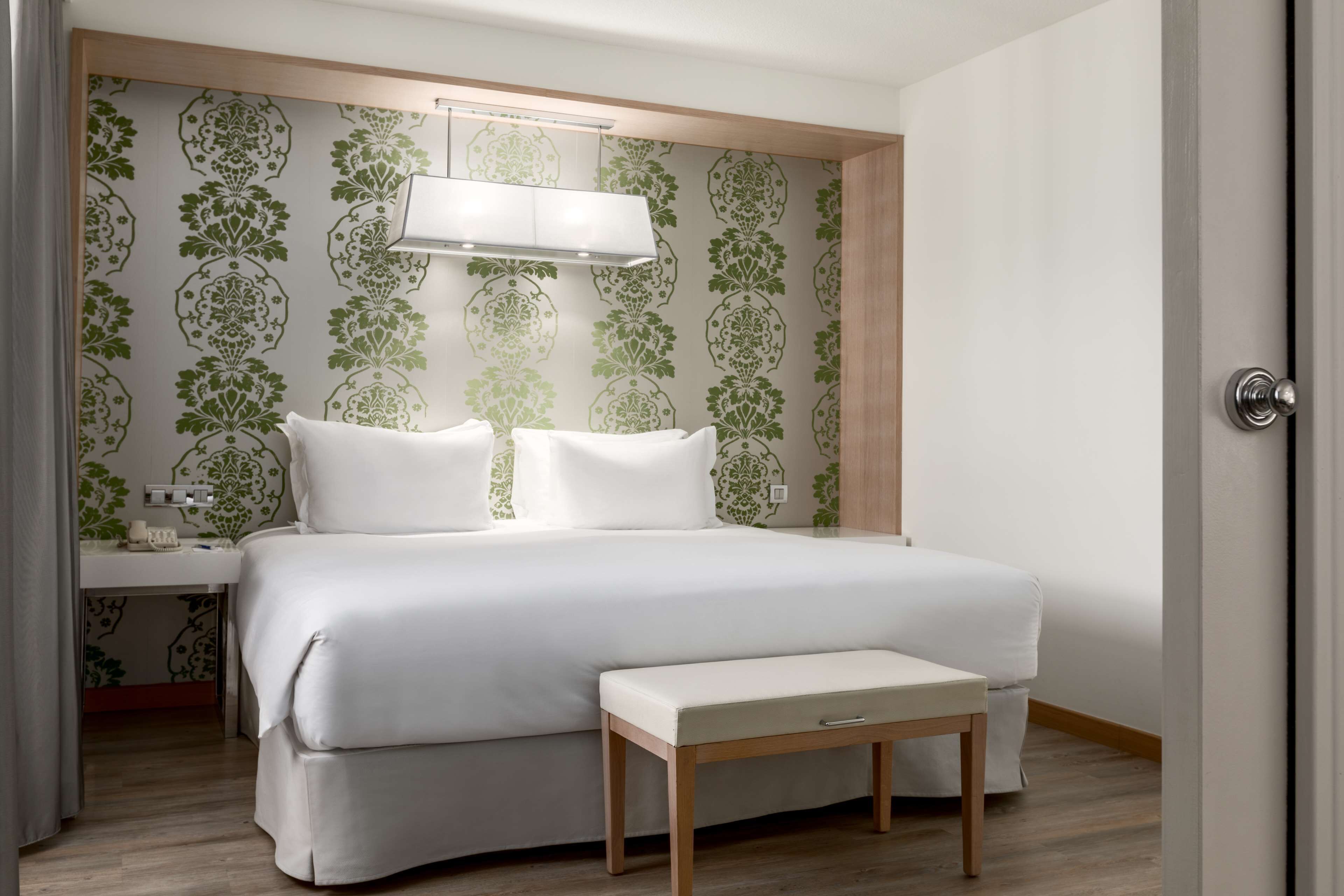 A neatly arranged bedroom with a bed, bedside table, and a bench.
