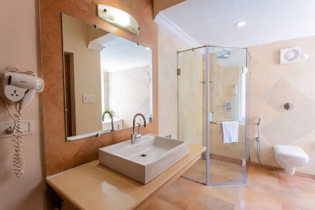A modern bathroom with a large mirror, a sink, a glass shower enclosure, and a toilet.