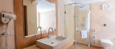 A modern bathroom with a large mirror, a sink, a glass shower enclosure, and a toilet.