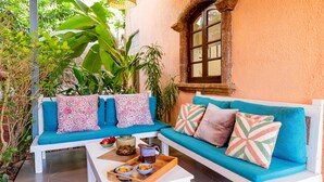 A cozy seating area with a white bench and a blue sofa, both adorned with patterned cushions. A wooden tray with bowls and a pitcher is placed on a white table in front of the bench. - Aguada Anchorage - The Villa Resort (Candolim)