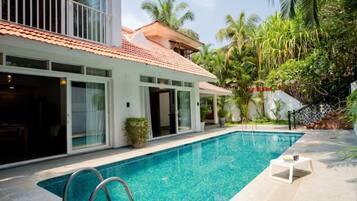 A modern house with a swimming pool, large windows, and a balcony.