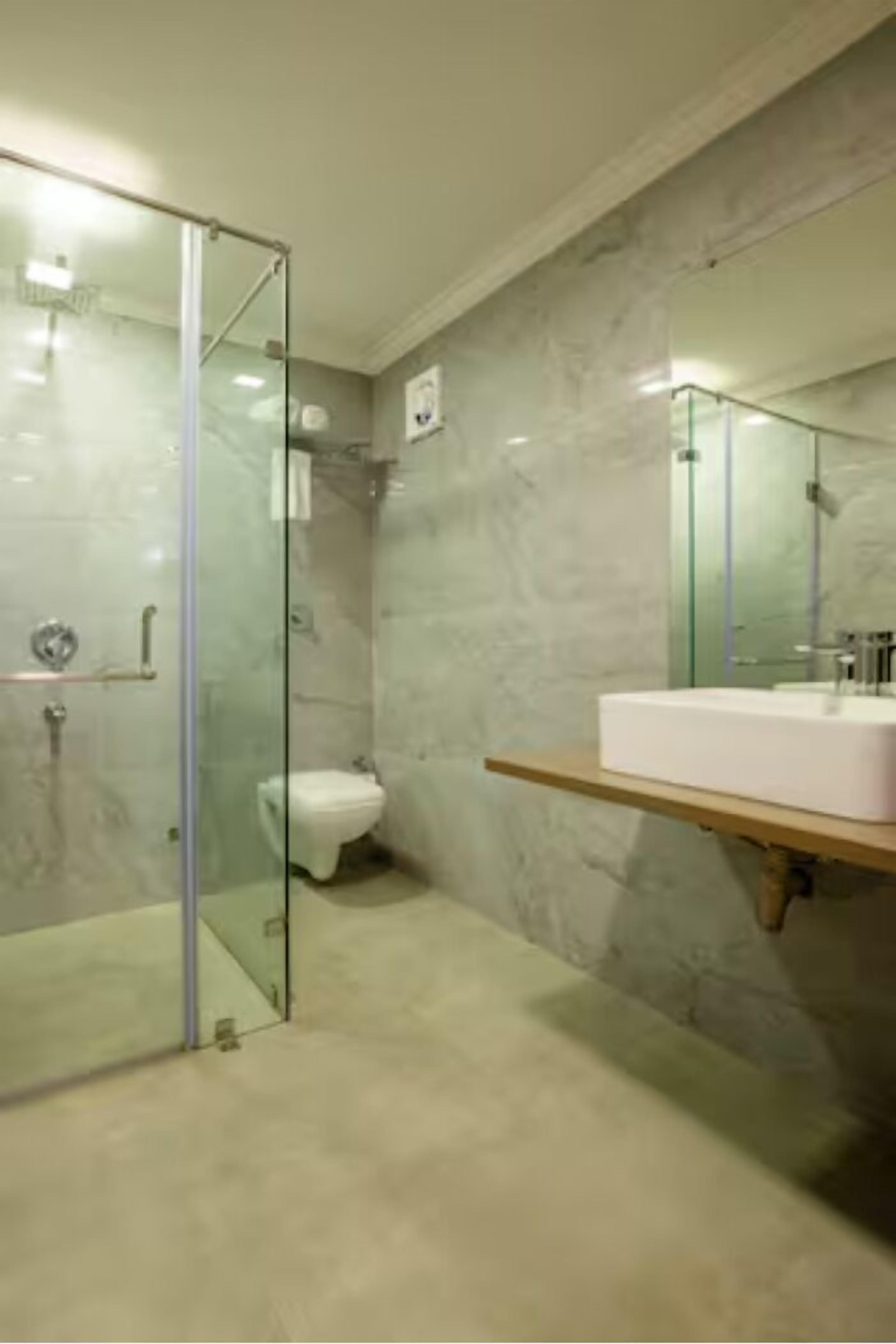 A modern bathroom with a glass-enclosed shower, a white sink, and a marble wall.