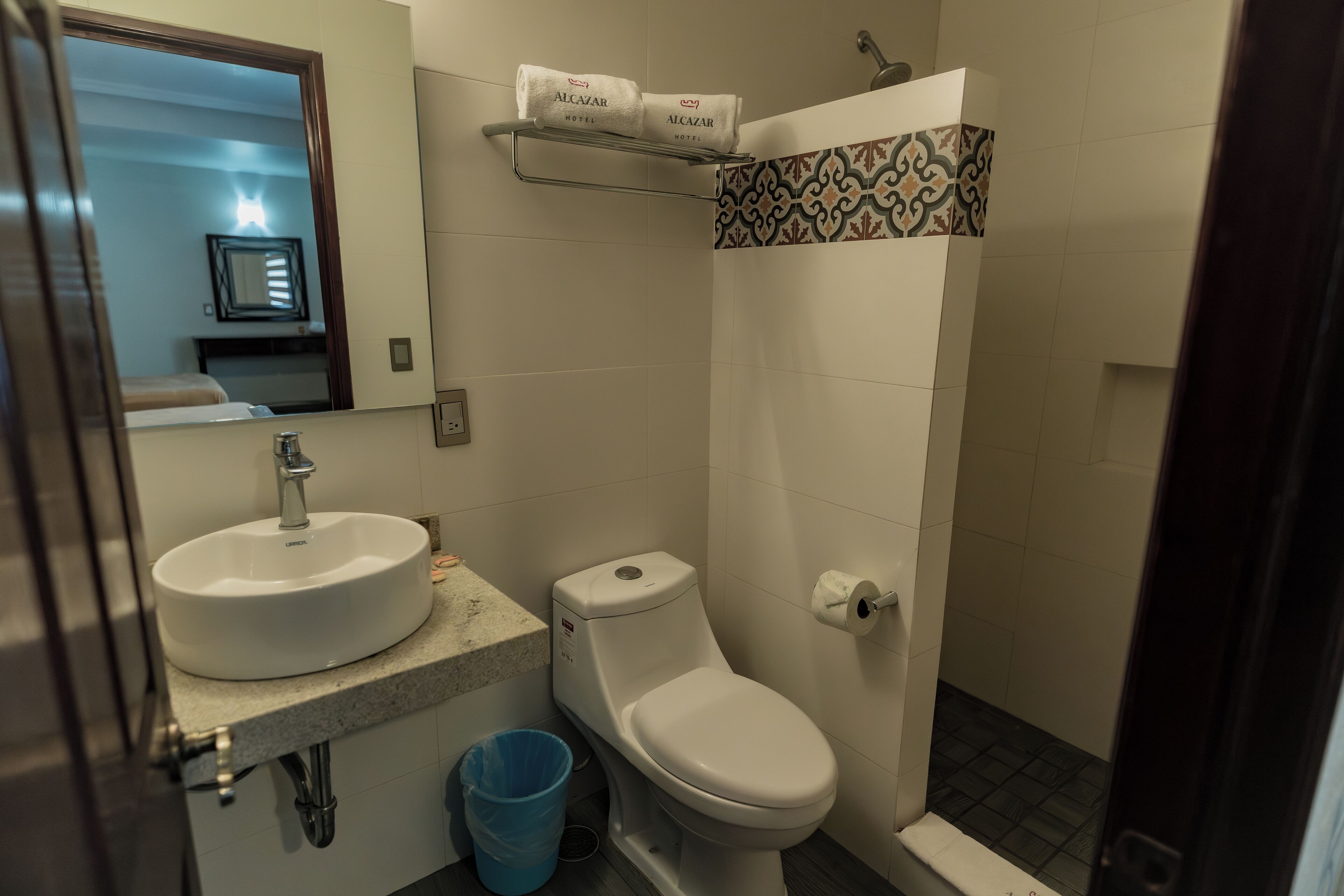 A bathroom with a sink, toilet, and shower. There are two towels on a shelf above the toilet.