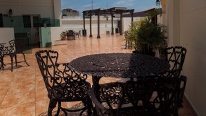 An outdoor patio with a round table and chairs, a pergola, and potted plants. - Hotel Alcazar (Guadalajara)