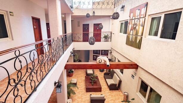 A multi-level atrium with a central staircase, decorative lanterns, and a white sculpture. - Hotel Alcazar (Guadalajara)