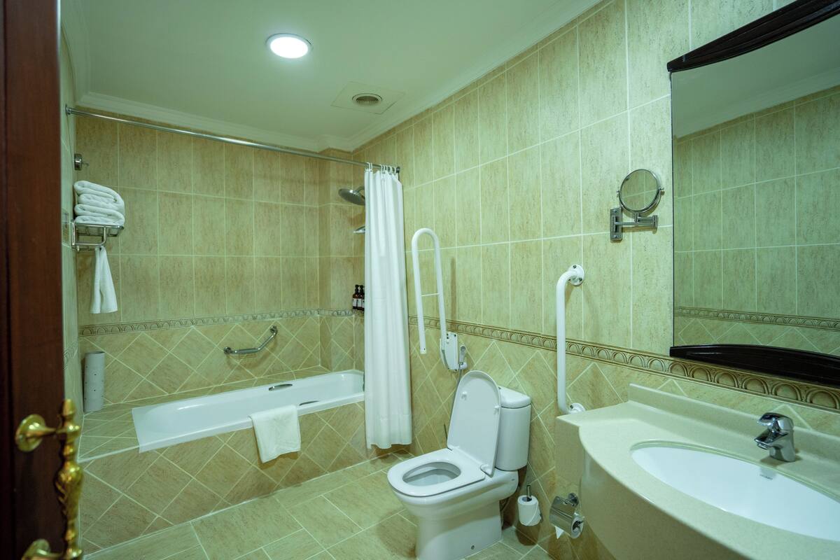 A bathroom with a bathtub, toilet, sink, and a mirror.