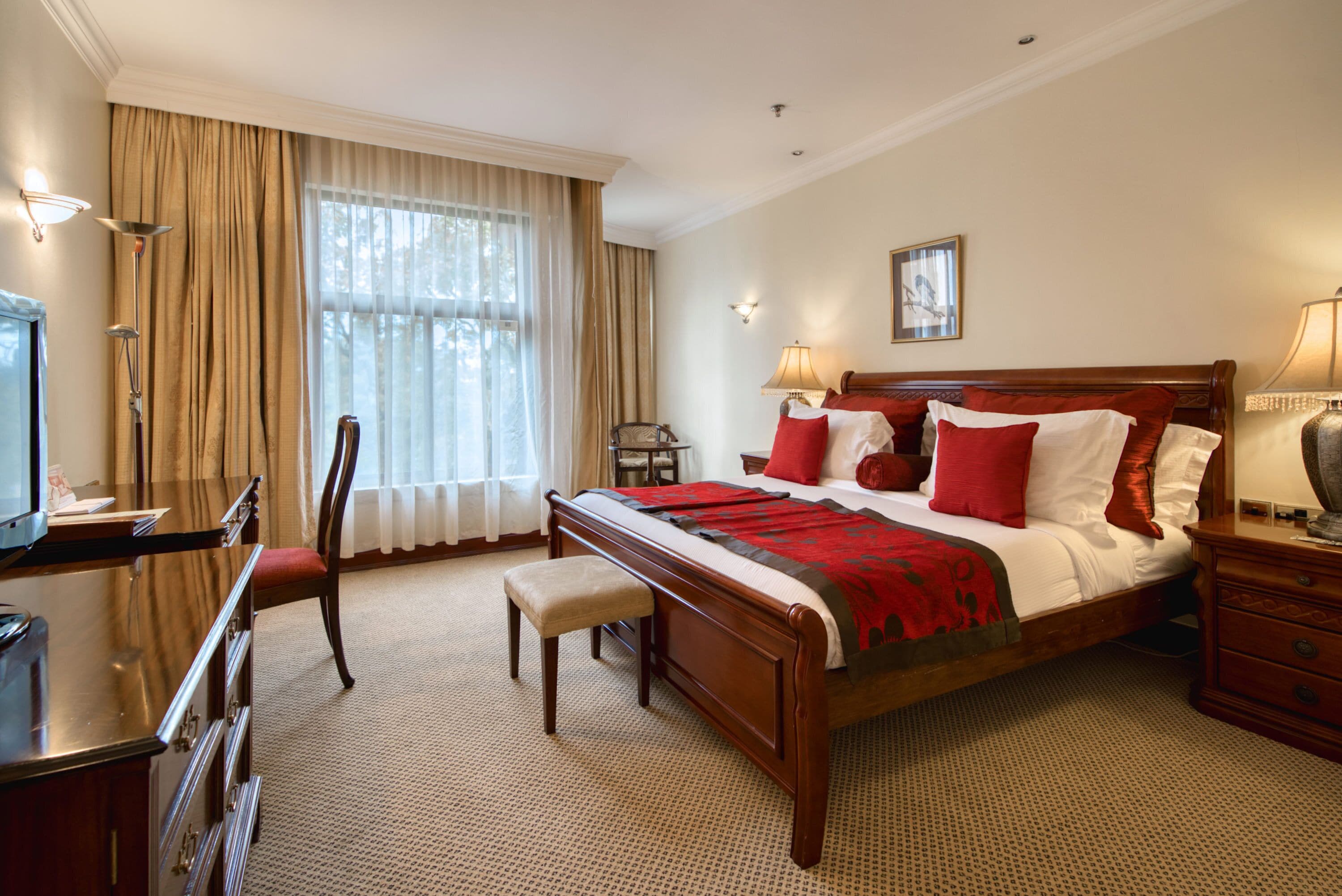 A hotel room with a large bed, a desk, a chair, and a television.
