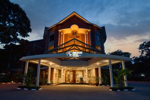 Un hotel con entrada central, una zona cubierta con columnas y un letrero que indica que es el Kido Palace Hotel.