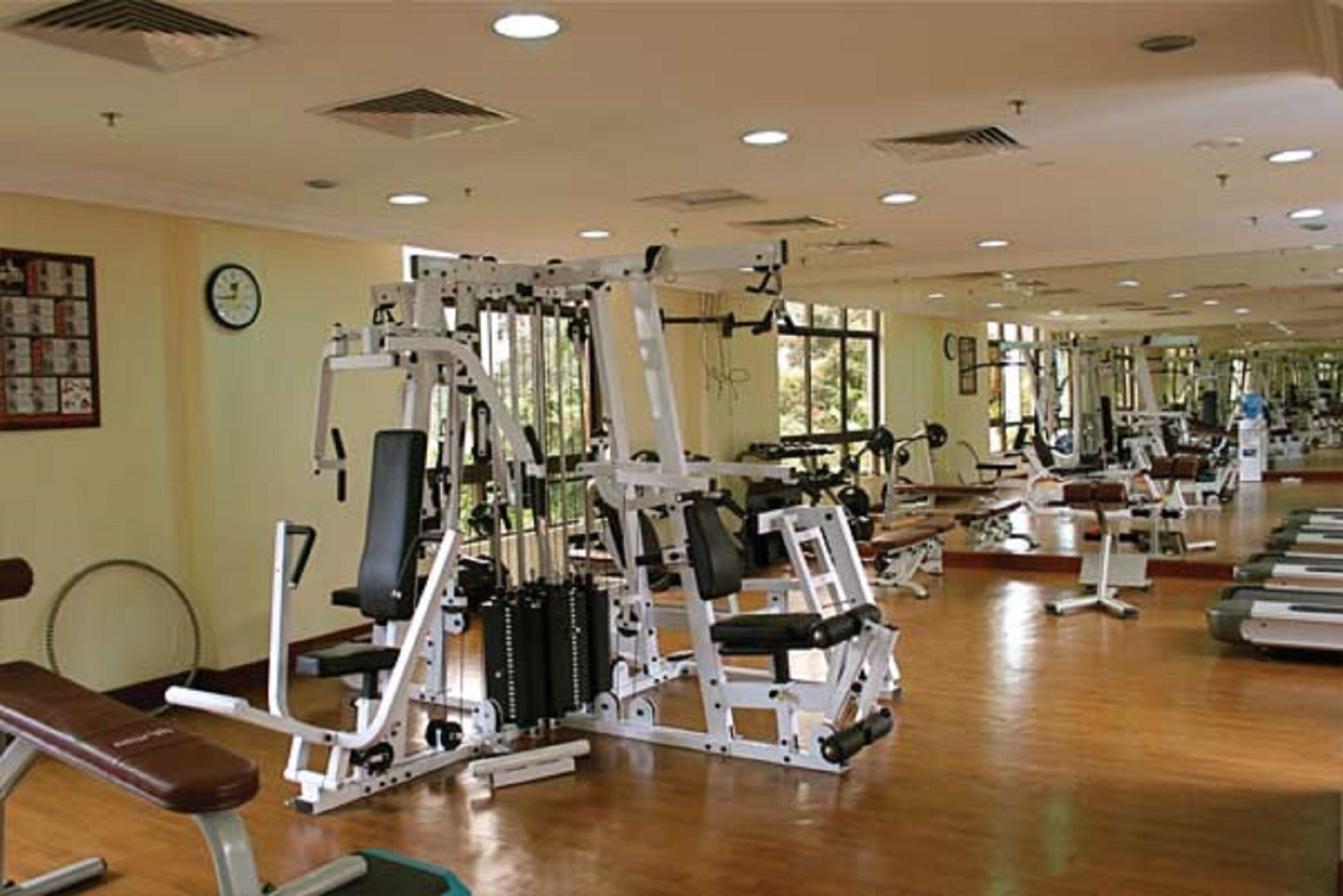 Un gimnasio con diversas máquinas de ejercicio, una banca y espejos en las paredes.