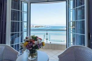 Una habitación con vista al mar, una mesa con un florero y dos sillas.