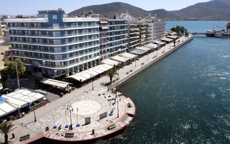 A waterfront hotel with a circular plaza, multiple balconies, and a view of the sea.