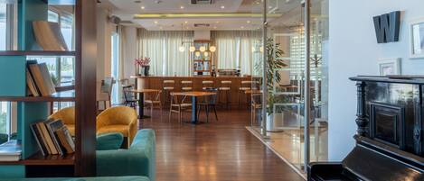 A modern interior with a piano, a sofa, and a dining area with chairs and a table.