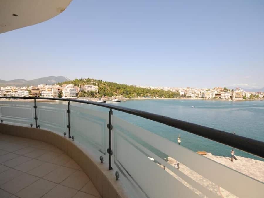 A balcony with a view of a waterfront cityscape, including buildings and a distant hill.