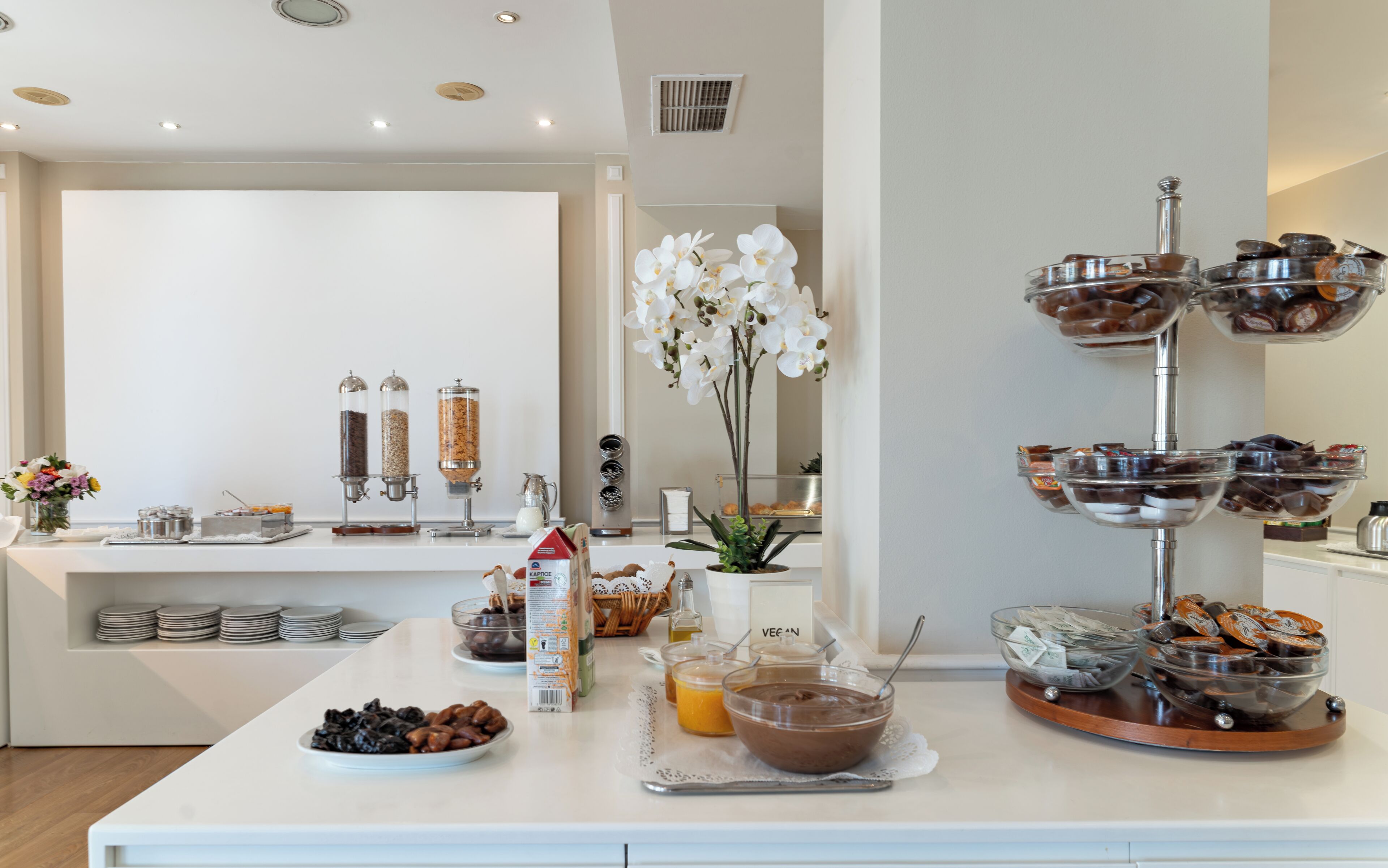 Un bufé de desayuno con diversas opciones de comida y una orquídea blanca decorativa.